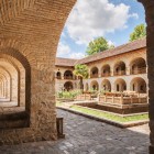 Portici in pietra e arcate si aprono sul cortile del Caravanserraglio di Sheki, con giardino centrale e atmosfere storiche nel cuore del Caucaso