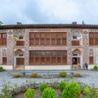 Il Palazzo del Khan di Sheki affascina con mosaici colorati, vetrate shebeke e motivi geometrici, incorniciato da un elegante e suggestivo cortile verde.