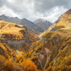 Spettacolare paesaggio autunnale lungo la Strada Militare Georgiana: vallate dorate, canyon profondi e vette del Caucaso avvolte da nuvole, tra silenzi e natura selvaggia.