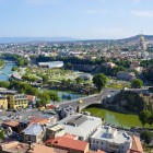 Panorama di Tbilisi con il fiume Kura, ponti moderni e chiese storiche arroccate sulle colline: un incontro armonioso tra architettura antica e contemporanea.