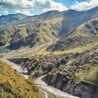 Piccoli villaggi punteggiano la valle lungo la Strada Militare Georgiana: colline verdi, fiumi sinuosi e montagne del Caucaso incorniciano un paesaggio autentico e suggestivo.