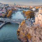 La Chiesa di Metekhi svetta sulla roccia sopra il fiume Kura, incorniciando ponti e skyline di Tbilisi in un suggestivo scenario urbano.
