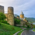La strada che conduce alla Fortezza di Ananuri attraversa verdi colline e conduce a torri medievali e chiese in pietra che dominano il suggestivo lago Zhinvali nel cuore della Georgia.