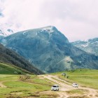 Salita in minivan 4x4 tra prati alpini e sentieri di montagna verso la Chiesa della Trinità di Gergeti, con spettacolari panorami sul Monte Kazbek e sulle vette del Grande Caucaso.