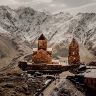 La Chiesa della Trinità di Gergeti (Tsminda Sameba) domina i paesaggi del Grande Caucaso vicino al villaggio di Gergeti, ai piedi del Monte Kazbek, simbolo iconico della Georgia.