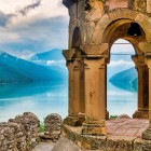 Vista panoramica dalla fortezza di Ananuri sul lago Zhinvali: antiche arcate in pietra incorniciano le acque turchesi e le montagne del Caucaso creando un paesaggio suggestivo.