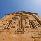 Dettaglio della croce scolpita sulla facciata della chiesa di Ananuri: raffinati bassorilievi medievali decorano la pietra, testimonianza dell’arte sacra georgiana del XVII secolo.