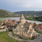 Vista aerea della maestosa Cattedrale di Svetitskhoveli a Mtskheta, antico centro religioso della Georgia, con il fiume Mtkvari e le colline verdi che circondano la città.