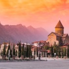 La Cattedrale di Svetitskhoveli a Mtskheta al tramonto, avvolta da calde luci dorate, con le montagne del Caucaso sullo sfondo e l’atmosfera suggestiva dell’antica capitale della Georgia.