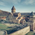 Vista aerea della Cattedrale di Svetitskhoveli a Mtskheta, capolavoro dell’architettura medievale georgiana, circondata da antiche mura e dalle colline della valle del fiume Mtkvari.