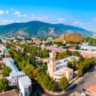 Vista aerea di Gori, in Georgia, con la storica Fortezza di Gori che domina la città dall’alto della collina, circondata da quartieri moderni e dalle montagne del Caucaso.