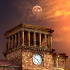 La torre dell’orologio del Palazzo del Governo in Piazza della Repubblica a Yerevan, Armenia, illuminata dal caldo tramonto con la luna che appare nel cielo sullo sfondo.