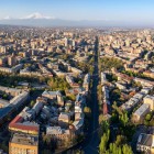 Vista aerea di Yerevan con il vivace corso Mashtots che attraversa la città tra palazzi, viali alberati e quartieri storici, con il maestoso Monte Ararat all’orizzonte.