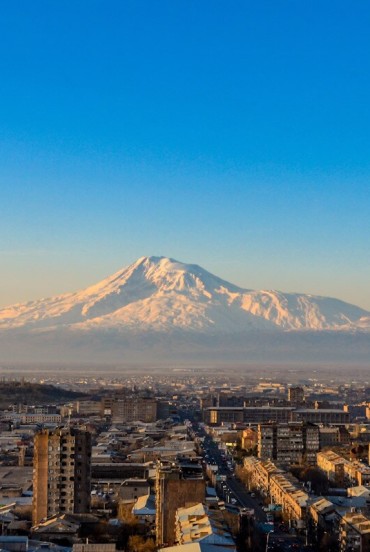 Vista panoramica all’alba del Monte Ararat che si innalza maestoso sopra il quartiere Sebastia-Malatia di Yerevan, Armenia, illuminando la città con i caldi colori del mattino.