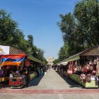 Mercato Vernissage di Yerevan con bancarelle di souvenir artigianali, tessuti e oggetti tradizionali, tra colori vivaci e atmosfera autentica sotto il cielo estivo.
