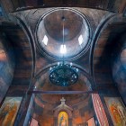 Interno del monastero di Khor Virap con volte in pietra e cupola centrale su tamburo, linee essenziali e luce soffusa che creano un’atmosfera spirituale.