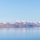 Vista del Lago Sevan, Armenia: acque calme e cristalline riflettono le montagne innevate, creando un paesaggio alpino suggestivo e una delle mete naturali più iconiche del Paese.