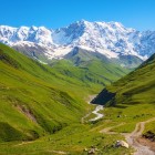 Paesaggio montano della Svaneti con verdi vallate e vette innevate del Caucaso. Natura incontaminata e scenari spettacolari ideali per trekking e avventura.