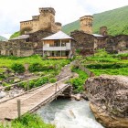 Veduta di Ushguli ai piedi del monte Shkhara, tra torri in pietra e antiche case. Un villaggio pittoresco della Svaneti immerso in scenari montani spettacolari.