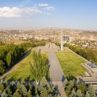Vista del memoriale di Tsitsernakaberd a Yerevan, simbolo del Genocidio Armeno, immerso in un parco con viali alberati e vista panoramica sulla città.