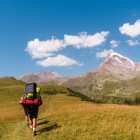 Sentiero panoramico tra prati dorati e dolci colline, con il maestoso Monte Kazbek sullo sfondo. Un trekking immerso nella natura selvaggia del Caucaso georgiano.