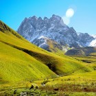 Valle verde e luminosa ai piedi del Monte Chaukhebi, dove sentieri sinuosi attraversano pascoli alpini e conducono verso spettacolari vette del Caucaso georgiano.