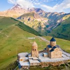 La Chiesa della Trinità di Gergeti domina le colline sopra Stepantsminda, affacciata sulle vallate del Kazbegi con il profilo del Monte Kazbek sullo sfondo.