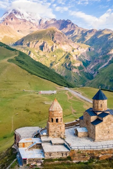 La Chiesa della Trinità di Gergeti domina le colline sopra Stepantsminda, affacciata sulle vallate del Kazbegi con il profilo del Monte Kazbek sullo sfondo.