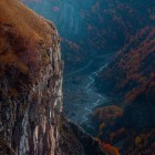 Veduta sulle montagne di Gudauri in autunno, dove gole profonde, pareti rocciose e boschi color rame disegnano paesaggi intensi nel cuore del Caucaso georgiano.