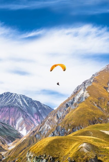 Parapendio tra le vette di Gudauri, con il volo che regala una prospettiva unica sulle montagne del Caucaso e sui vasti panorami dell’alta Georgia.