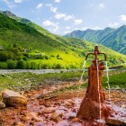 Sorgente di acqua minerale nella Gola di Khada, dove le acque ferruginose emergono tra i prati alpini e le montagne verdi del Caucaso georgiano.