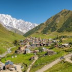 Villaggio di Ushguli adagiato tra prati e montagne nello Svaneti. Tra torri medievali e case in pietra, il fiume accompagna la vita lenta con lo Shkhara sullo sfondo.