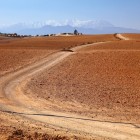 Pista sterrata nel deserto di Agafay, tra colline aride e ampi spazi aperti con le montagne dell’Atlante sullo sfondo.