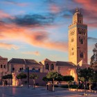 La Moschea Koutoubia domina Marrakech con il suo iconico minareto, simbolo della città imperiale, tra giardini eleganti e atmosfere suggestive al tramonto.