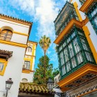 Eleganti balconi in stile andaluso si affacciano sulle vie storiche di Siviglia, dove architettura moresca, colori vivaci e tradizioni secolari creano un'atmosfera unica.
