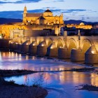 Il Ponte Romano conduce alla magnifica Moschea-Cattedrale di Cordova, dove luci, storia e fascino andaluso si riflettono sul fiume Guadalquivir in uno scenario indimenticabile.