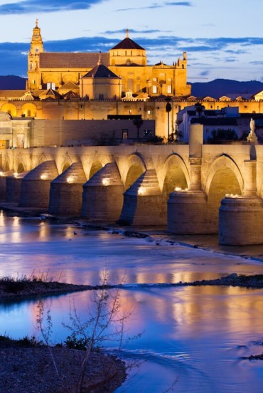 Il Ponte Romano conduce alla magnifica Moschea-Cattedrale di Cordova, dove luci, storia e fascino andaluso si riflettono sul fiume Guadalquivir in uno scenario indimenticabile.