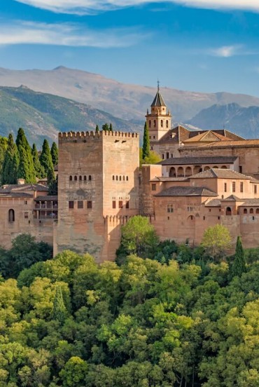 L'Alhambra domina Granada con le sue mura, torri e palazzi nazarí ai piedi della Sierra Nevada. Un capolavoro dell'arte islamica e simbolo senza tempo dell'Andalusia.