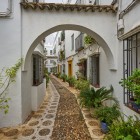 Un suggestivo arco introduce ai vicoli della Judería di Cordova, dove case bianche, ciottoli e piante mediterranee creano uno degli angoli più autentici e affascinanti dell'Andalusia.