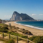 La lunga spiaggia dorata di Gibilterra accompagna lo sguardo fino all'imponente Rocca, dove il Mediterraneo incontra l'Atlantico regalando un panorama unico e senza tempo.