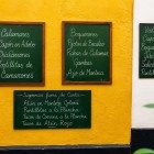 Le lavagne all'ingresso di una tipica taverna di Cadice presentano tapas e specialità di mare, invitando a scoprire i sapori autentici della tradizione gastronomica andalusa.