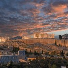 Al tramonto, l'Acropoli domina Atene con il Partenone illuminato che risplende sulla collina sacra. Un panorama senza tempo dove storia, cultura e fascino si incontrano.