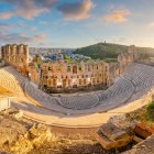 La luce dorata avvolge il Teatro di Erode Attico, dove le antiche gradinate sembrano ancora attendere voci e applausi. Atene si racconta in un istante sospeso.