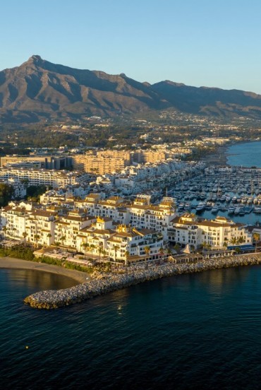 Puerto Banús si svela dall'alto tra yacht esclusivi, mare turchese e raffinata architettura mediterranea. Sullo sfondo, La Concha rende il panorama di Marbella ancora più spettacolare.