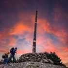 Due pellegrini raggiungono la Cruz de Ferro al tramonto, il luogo più simbolico del Cammino di Santiago, dove lasciano una pietra come segno di speranza e rinascita