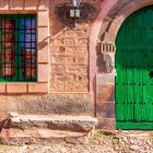 Dettaglio di una tradizionale abitazione in pietra di Castrillo de los Polvazares, con il caratteristico portone verde e l'architettura che racconta il passato dei mulattieri.