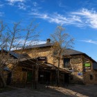 Facciata in pietra di un'antica locanda a Foncebadón, storico villaggio del Cammino di Santiago, immersa nella quiete della montagna sotto un limpido cielo attraversato da leggeri cirri.