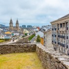 Passeggiando lungo le mura romane di Lugo, Patrimonio UNESCO, lo sguardo si apre sulla Cattedrale di Santa Maria e sui tetti del centro storico, nel cuore della Galizia.