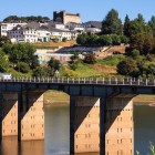 Veduta di Portomarín con il ponte sul fiume Miño e la Chiesa-Fortezza di San Nicola che domina il borgo, una delle tappe più iconiche del Cammino di Santiago.