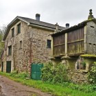 Una tipica casa in pietra della Galizia con il tradizionale hórreo, antico granaio sopraelevato, accompagna i pellegrini lungo il Cammino di Santiago tra storia e tradizioni rurali.